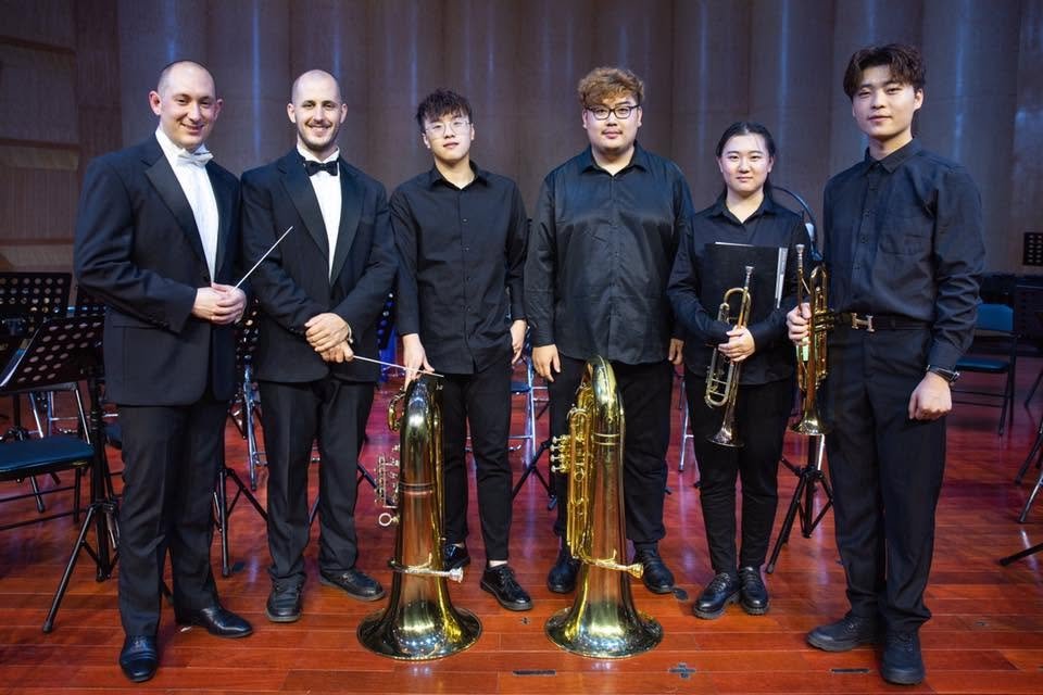 Matt Waters with low brass students holding euphoniums and tubas after a concert