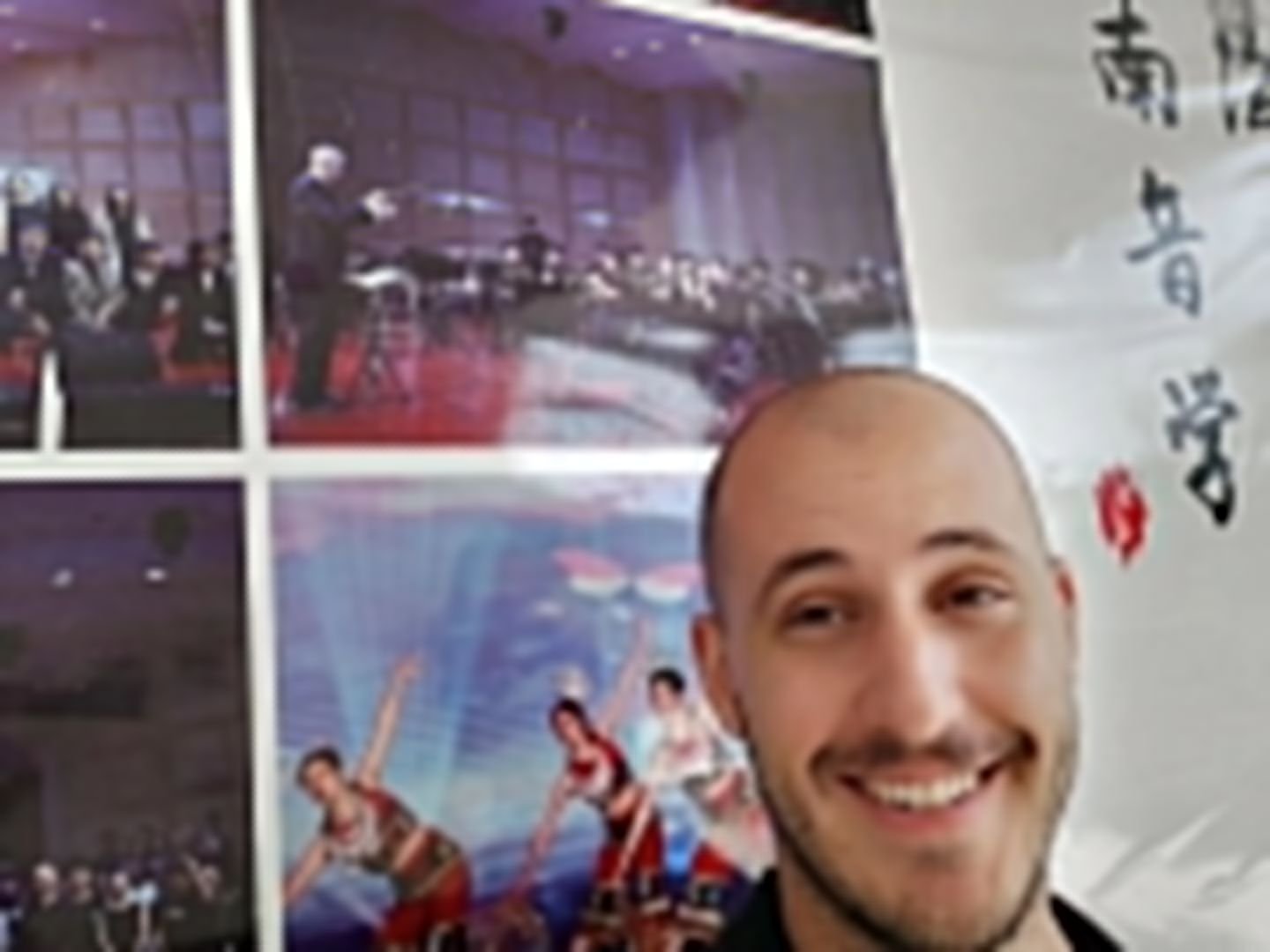 Matt Waters in front of a Nanhai Conservatory poster showing him conducting the wind orchestra